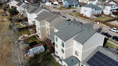 Gray architectural shingle roofs on a row of two-story homes, seen from above.