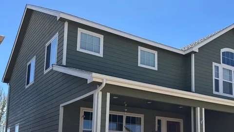 Green lap siding, white trim and white gutters on a two-story house with a covered front porch.