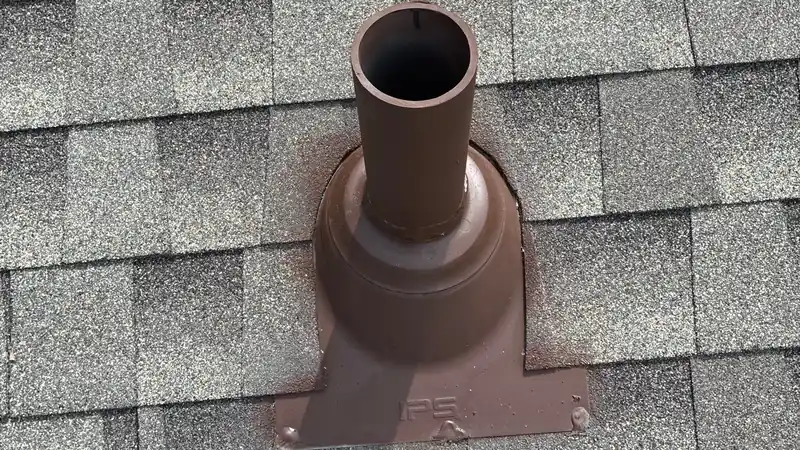 Brown painted pipe boot and vent pipe set into gray architectural shingles.