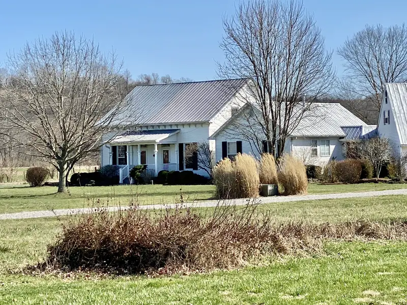 A white two-story farmhouse with a metal roof in Belleview, Kentucky